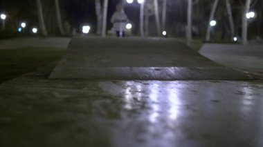 Çocuk, parktaki özel bir oyun parkında yokuş aşağı üç tekerlekli bir scooter sürüyor.