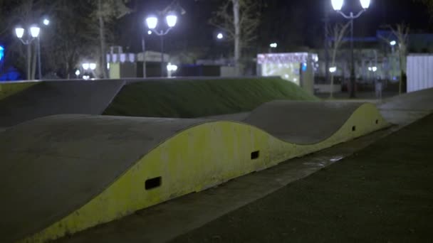 Les enfants montent un scooter à trois roues en descente sur une aire de jeux spéciale dans le parc — Video