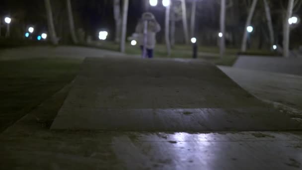 Το παιδί βόλτα με ένα τρίτροχο σκούτερ κατηφόρα σε μια ειδική παιδική χαρά στο πάρκο — Αρχείο Βίντεο