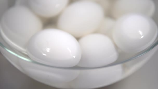 Huevos de pollo cocidos blancos yacen en un plato de agua y enfriados — Vídeo de stock