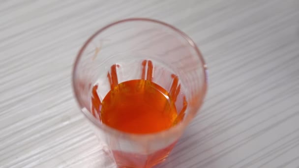 Doppa ett vitt hönsägg i ett glas med orange färg — Stockvideo