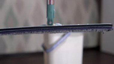 Hareketli yakın çekim, ev sahibi bir paspas alır ve yerleri siler.