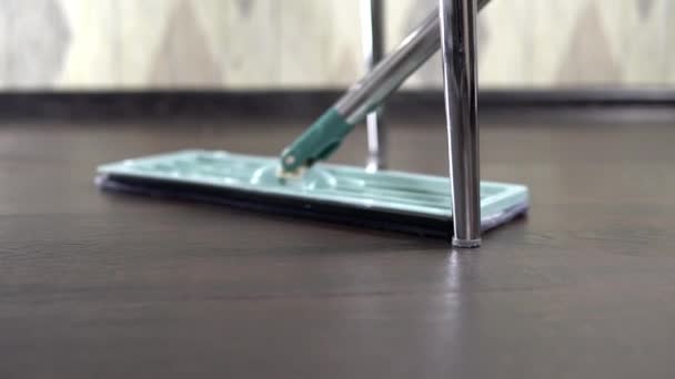 Tiroteio em close-up, a anfitriã limpa o chão perto da perna sob a cadeira — Vídeo de Stock