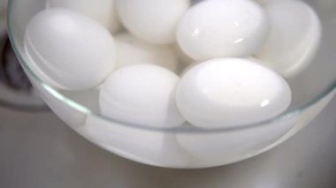 Beyaz haşlanmış tavuk yumurtaları bir tabak suda ve soğutulmuş.