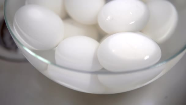 Jaja kurze gotowane na biało leżą w talerzu wody i schłodzone — Wideo stockowe