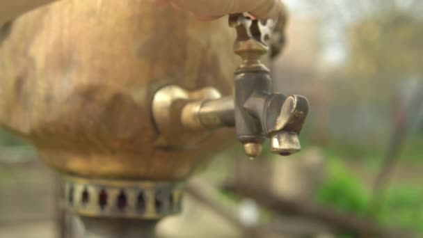 A womans hand opens the brass tap of the samovar and boiling water flows — Stock Video