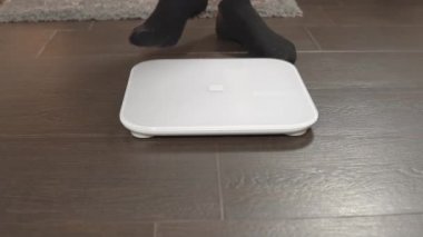 Adam teraziye çıkıyor. Tartının ağırlığı. Erkek bacakları teraziye yakın çekim. Fazla ağırlık kontrolü