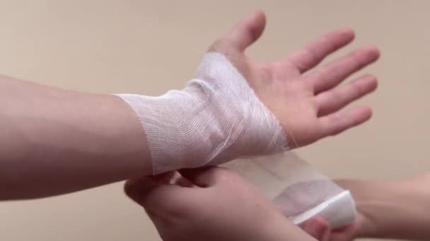 Крупним планом знімок зап'ястя руки чоловіка. Біль або рана на руці. Лікування рани. Обмотування пов'язки на руці — стокове відео