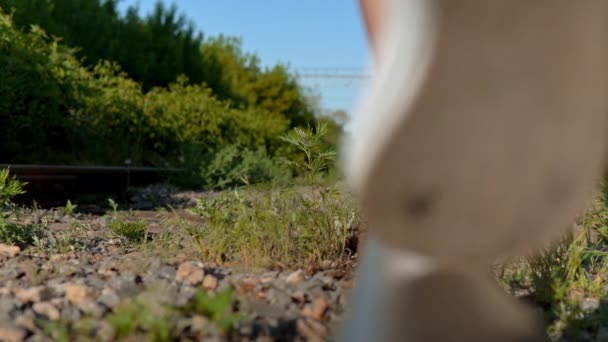 Close-up shot of a girl walking on the rails. Walk along the railroad tracks. Old train track — Stock Video