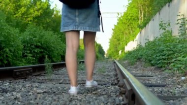 Sırtında sırt çantası olan bir kadın raylarda dinlenmek için oturdu. Demiryolu raylarında seyahat et. Eski tren yolu