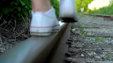 Raylarda yürüyen bir kızın yakın plan fotoğrafı. Tren yolu boyunca yürü. Eski tren yolu