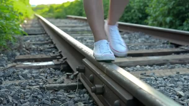 रेल पर चलने वाली लड़की का क्लोज-अप शॉट। रेल पटरियों के साथ चलो। पुराने ट्रेन ट्रैक — स्टॉक वीडियो