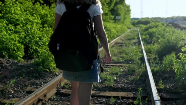 Uma menina com uma mochila caminha ao longo dos dormentes. Viaje em trilhos ferroviários. Velha via férrea — Vídeo de Stock