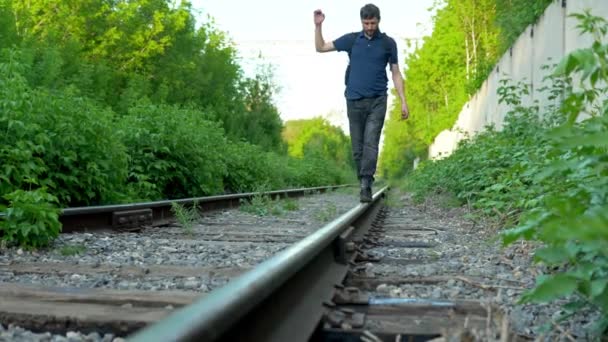 Um tiro de perto de um homem a andar sobre os carris. Caminhe pelos trilhos ferroviários. Velha via férrea — Vídeo de Stock