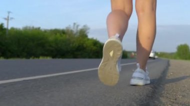 Bir kızın bacakları yolda yakından yürüyordu. Bir kadın yol boyunca yürür. Otostop çekiyordum.