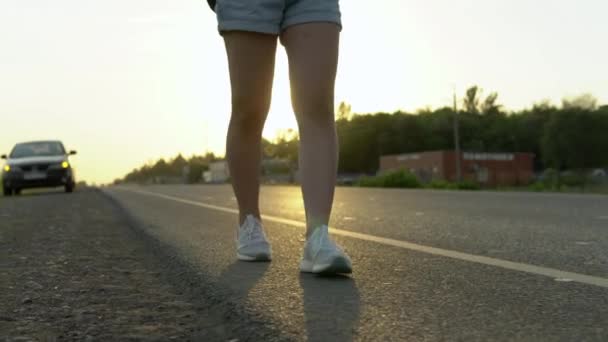 Primer plano de las piernas de las niñas contra el fondo de un coche defectuoso. Una mujer camina por el camino. — Vídeo de stock