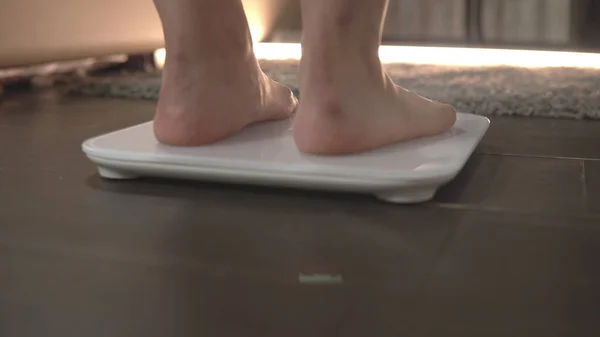 The girl gets on the scales. Weighing on scales. Close-up of female legs on the scales. Excess weight check — Stock Photo, Image