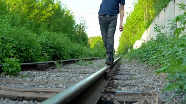 Raylarda yürüyen bir adamın yakın plan fotoğrafı. Tren yolu boyunca yürü. Eski tren yolu
