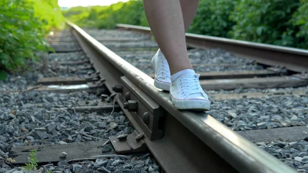 Close-up shot of a girl walking on the rails. Walk along the railroad tracks. Old train track — Stock Photo, Image