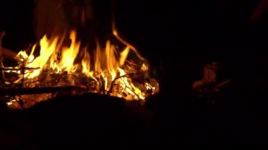 Gece ateşi. İnsanlar ateşin yanında karanlıkta oturur ve kendilerini ısıtırlar. Ateşin yanında kamp yapmak 4K