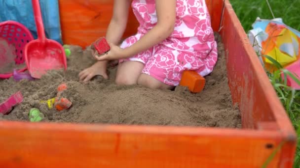 The girl plays in the sandbox. The child makes sand cakes. 4k — Stock Video