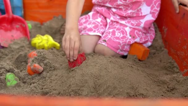 那女孩在沙坑里玩耍.这孩子做沙饼.4k — 图库视频影像