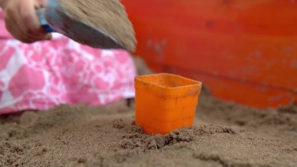 그 여자 애는 모래 상자에서 놀아요. 아이가 모래 케이크를 만듭니다. 4k — 비디오