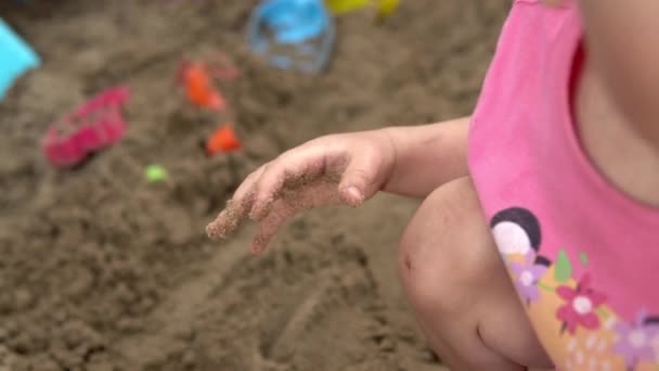 Niño con una mano untada con arena. Niños jugando en el arenero 4k — Vídeo de stock