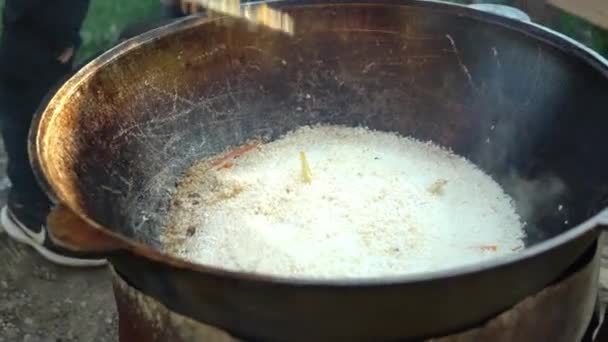 Matlagning över en eld i en kittel. Koka risrätter utomhus. 4k — Stockvideo