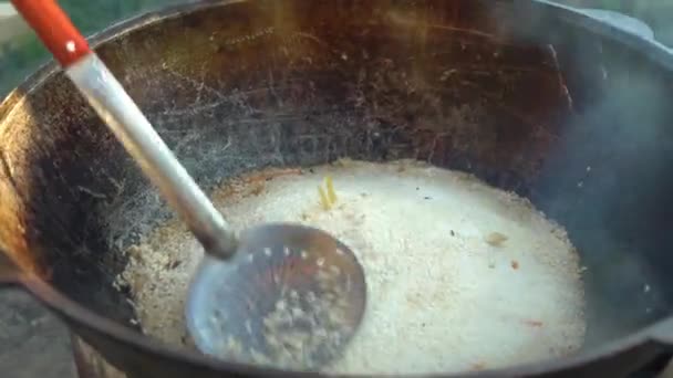 Готовить еду над костром в котле. Готовить блюда из риса на открытом воздухе. 4k — стоковое видео