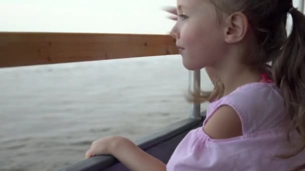 La chica a bordo del ferry en la perrilla mira hacia la inmensidad del río. Paseo en barco por el río 4k — Vídeo de stock