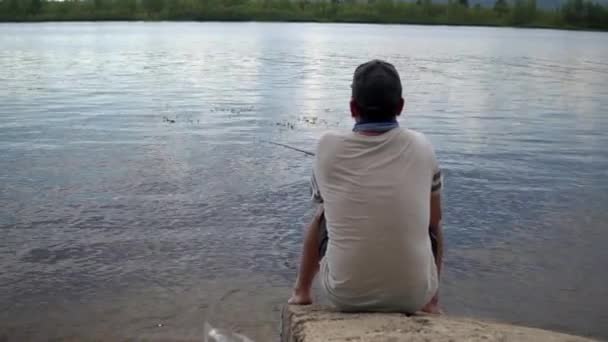 Un pescador junto al río en la orilla. El hombre está pescando. Pesca con una línea desde la orilla 4k — Vídeos de Stock