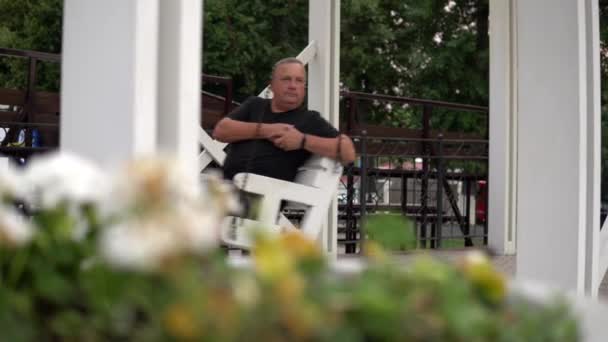 Viejo solitario balanceándose en un columpio en el parque. Una persona descansando en el parque 4k — Vídeos de Stock