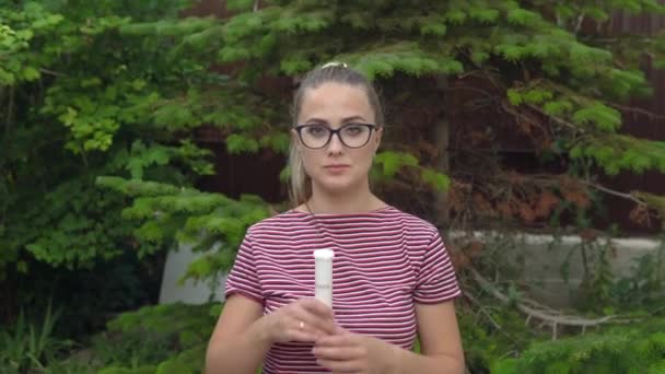 Una chica con gafas sostiene una cápsula en la mano y saca vitaminas. Mantener la inmunidad. Estilo de vida saludable. 4k — Vídeo de stock