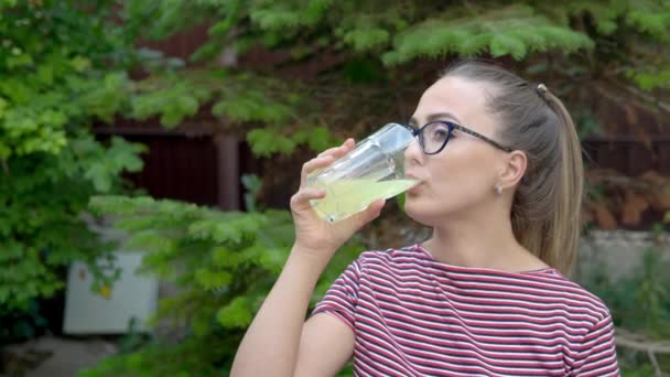 Ένα κορίτσι με γυαλιά κρατάει ένα ποτήρι με ένα βιταμινούχο ποτό στο χέρι και το πίνει με μια γουλιά. Διατήρηση ασυλίας. Υγιεινός τρόπος ζωής 4ια — Αρχείο Βίντεο