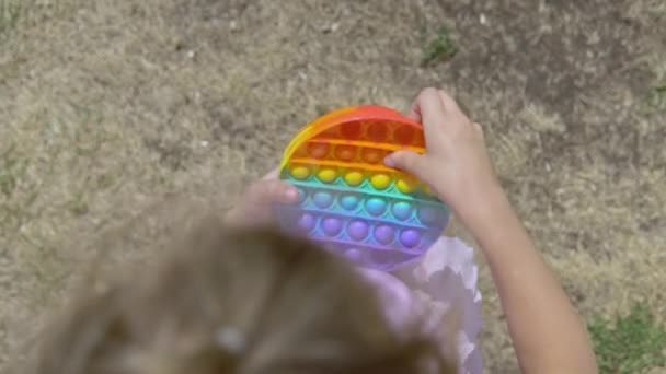 The girl in pink plays popit. The child is passionate about rainbow anti-stress. Childrens silicone toy — Stock Video
