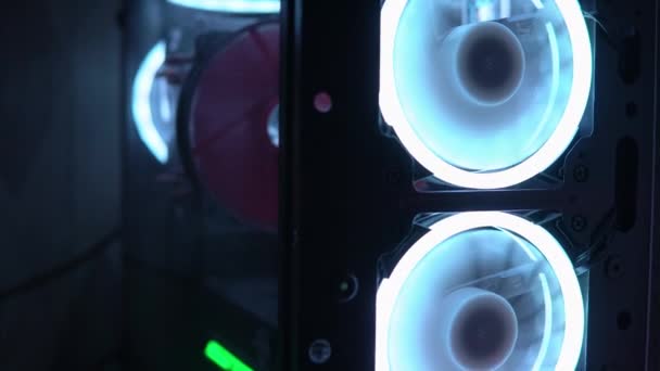 Niebieskie oświetlenie wentylatora w obudowie komputera. Niebieskie ostrza obracają się do chłodnych komponentów komputera. Komputer do gier świeci w ciemności. Piaskowe szkło boczne obudowy komputera — Wideo stockowe