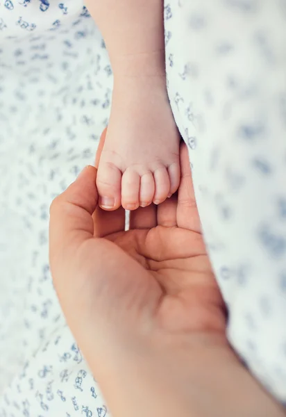 Mothers palm laying on the child blanket, fingers touching leg of her newborn son — Stock Photo, Image