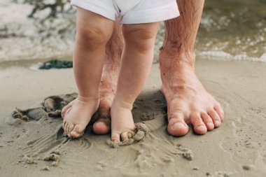 Çıplak ayak baba ve küçük oğlu kum suya yakın kalmak. 