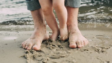 Çıplak ayak baba ve küçük oğlu kum suya yakın kalmak. 