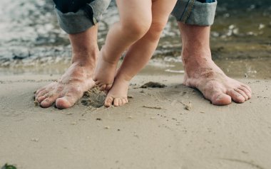 Çıplak ayak baba ve küçük oğlu kum suya yakın kalmak. 