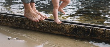 Çıplak ayak babası oğlunun Nehri yakınında beton raf tarafından yürüme yardım