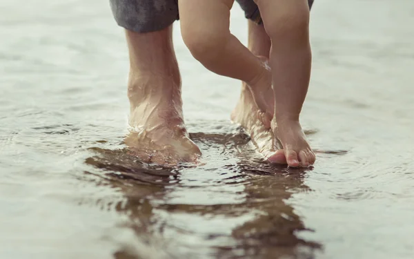 Padre piedi nudi e il suo piccolo figlio che rimane nell'acqua riflettente — Foto Stock