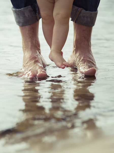 Bare feet father and his little son staying in the reflecting water