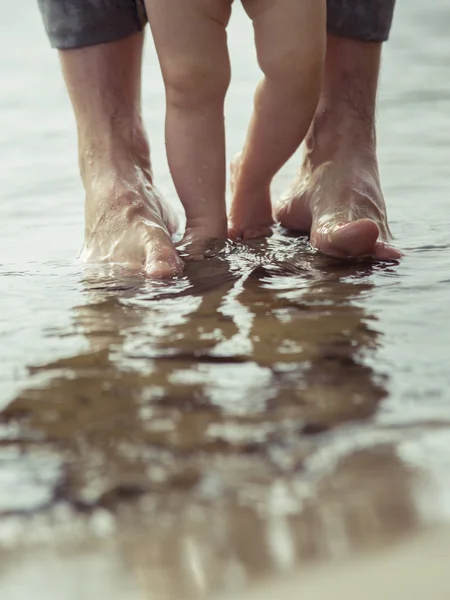 Bare feet father and his little son staying in the reflecting water — Stock Photo, Image