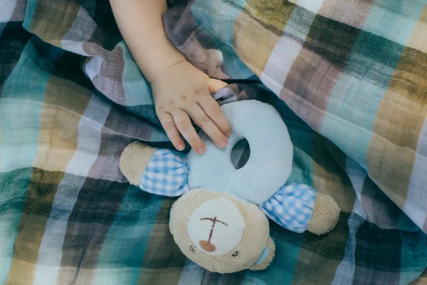 Hand van kleine peuter raken de teddybeer rammelaar — Stockfoto