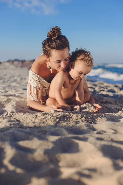 Mutlu anne ve oğlu yaz aylarında kumsalda oynarken