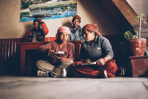 CIRCA, NEPAL, - 09 NOVEMBRO 2012 - Caminho de trekking Annapurna. Nepal mulher fazendo comida tradicional - tsampa. Homens sentados ao lado da mulher . — Fotografia de Stock