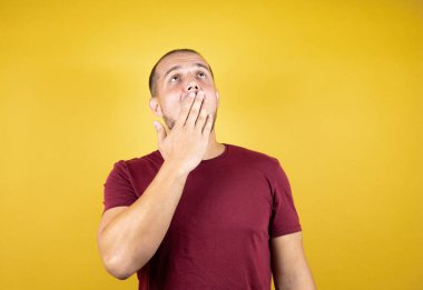 Sarı izole arka plan üzerine kırmızı tişört giyen Rus adam ağzıyla esnemekten sıkılmış. Huzursuz ve uykulu..