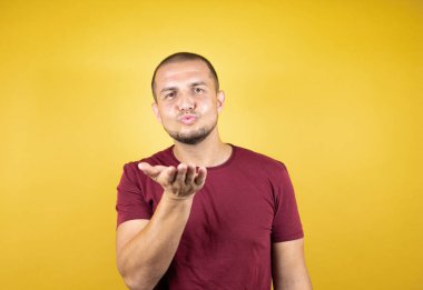 Rus adam, sarı tişörtlü, tipik kırmızı tişörtlü, izole edilmiş arka planda kameraya bakıp havada öpüşürken güzel ve seksi görünüyor. Aşk ifadesi.
